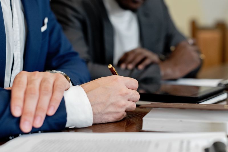 Abogados revisando y firmando documentos en una mesa de reuniones